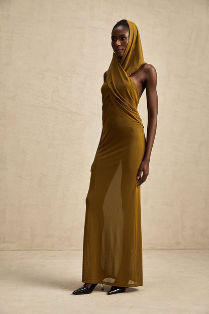 Woman wearing long flowing maxi dress with hood and open back design in crossover style