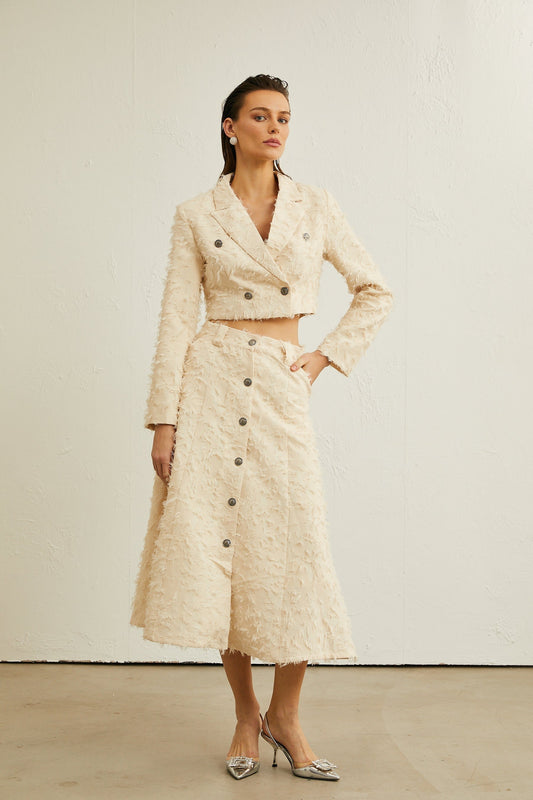 Woman wearing white fringed jacket and matching skirt set styled with bohemian flair