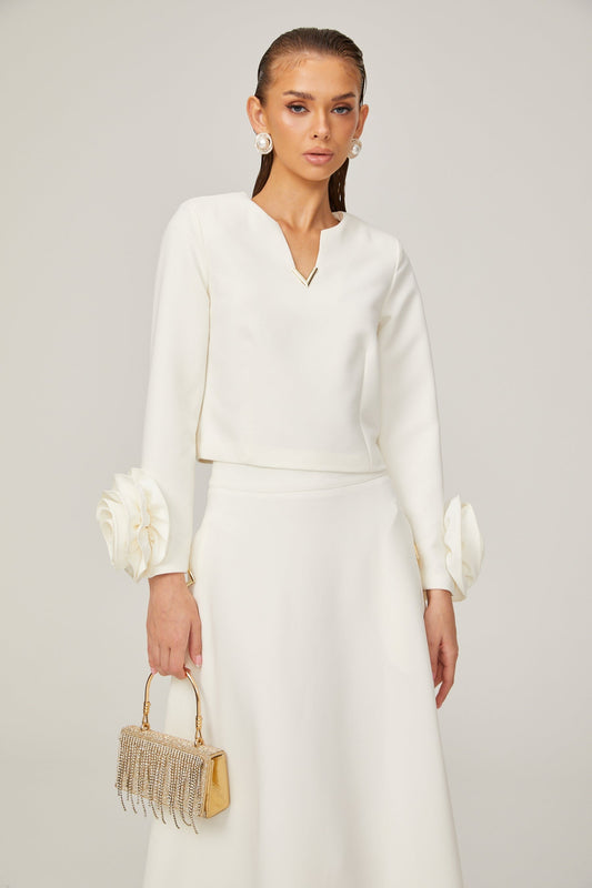 Woman wearing white matching set with top and skirt featuring threedimensional petal details