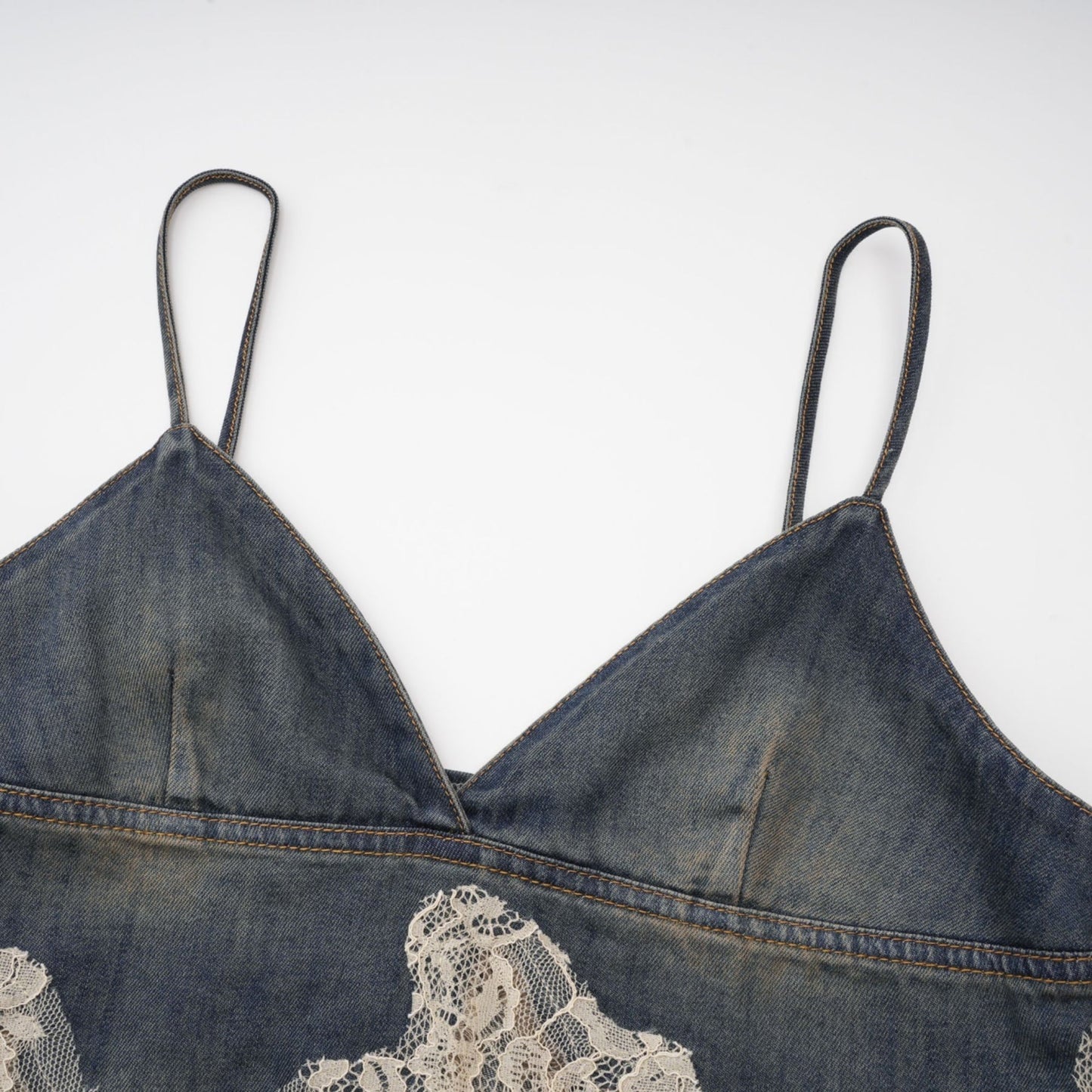 Young woman wearing a matching denim outfit consisting of a lacedetailed top and shorts with frayed edges standing against a plain background