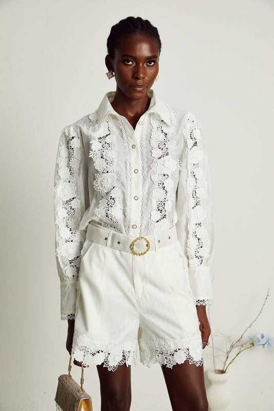 Young woman wearing a white lace trim embroidered shirt with matching shorts in a sunny outdoor setting